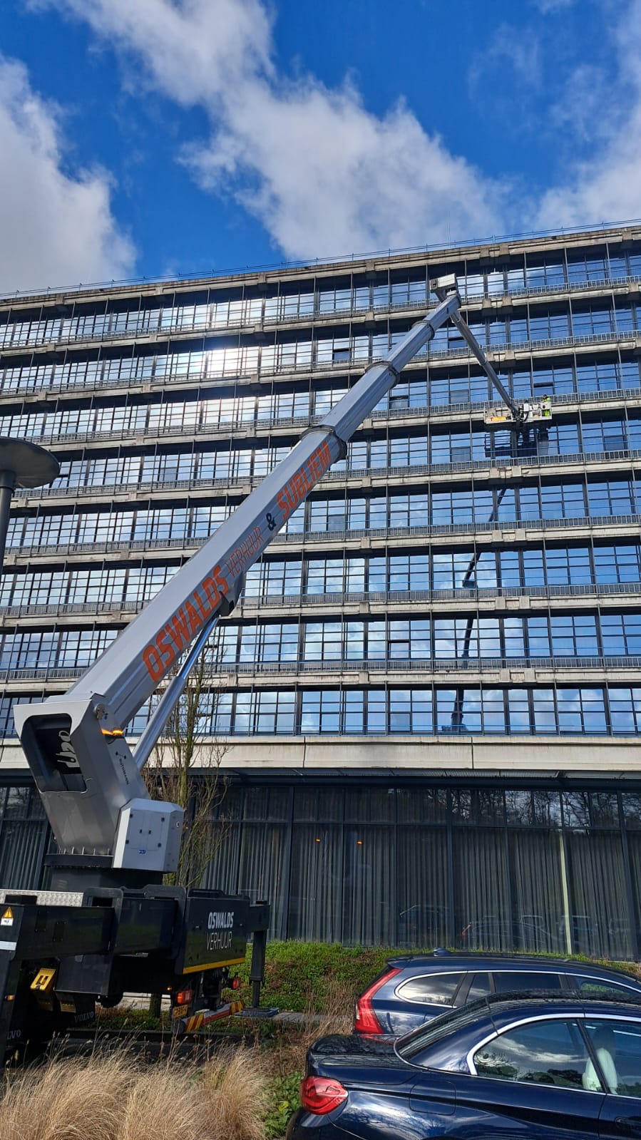 Subliem hoogwerker bij een groot kantoorpand